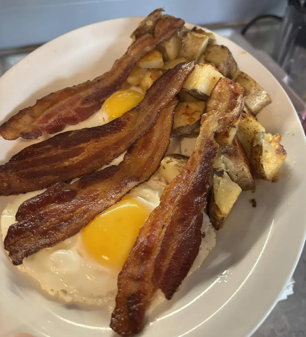 Fried eggs with crisp bacon and home fries on a plate