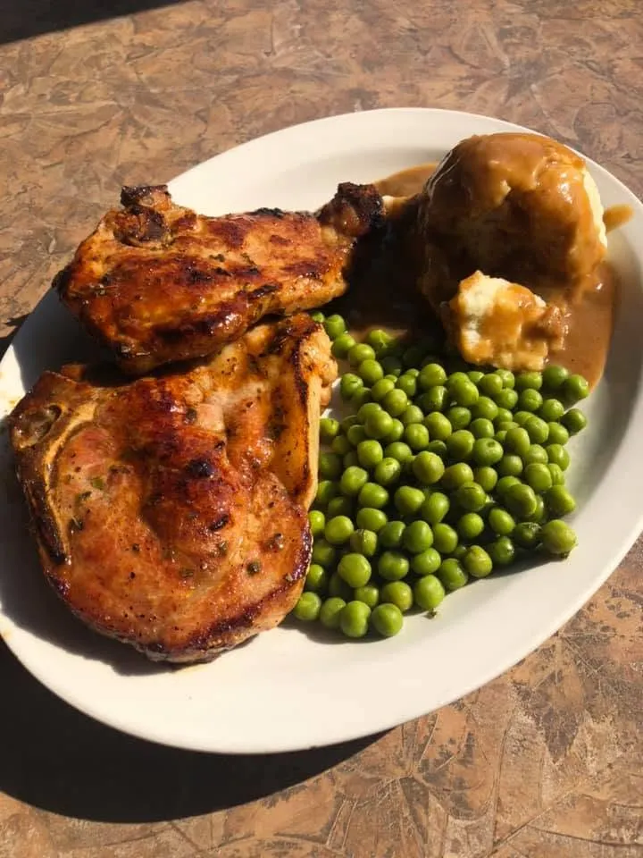 Grilled pork chops with mashed potato and gravy, and green peas